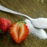 Close-up of fresh strawberries with sugar on a wooden table. Perfect for healthy dessert ideas.