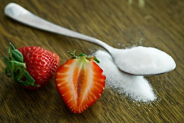 Compliance bei Ernährungstherapien: Was beeinflusst die Therapietreue? Close-up of fresh strawberries with sugar on a wooden table. Perfect for healthy dessert ideas.