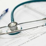 A stethoscope and pen resting on a medical report in a healthcare setting.