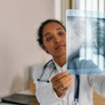 Healthcare professional analyzing chest X-ray in modern medical office.