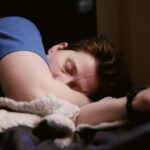 woman in blue shirt lying on bed