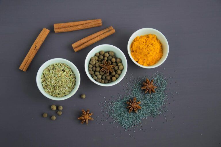 Pflanzliche Arzneimittel bei Colitis ulcerosa – Was Sie wissen sollten Flat lay of assorted spices including cinnamon, turmeric, and star anise on a dark surface.