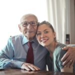 A joyful elderly man and young woman sharing an affectionate embrace indoors.