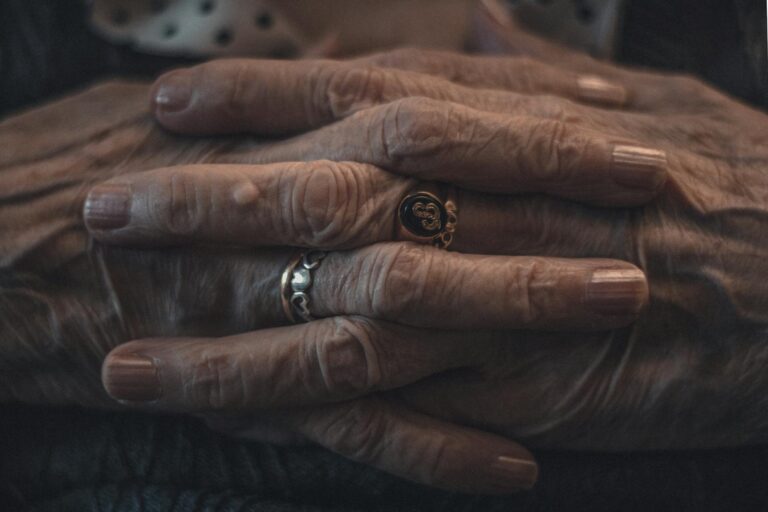 Intimate close-up of elderly hands adorned with rings, showcasing wrinkles and age.