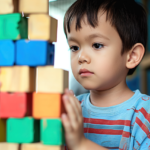 ai generated, young boy, puzzle, autism, autism awareness, building blocks, colorful, wooden blocks, tower, concentration, indoor activity, playtime, hand-eye coordination, cognitive development, focused, educational toys, learning, preschooler, enjoyment, skill building, patience, preschool activity, developmental toys, balancing, stripes, montessori, autism, autism, autism, autism, autism, montessori