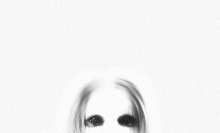Schizoide Persönlichkeitsstörung: Was wirklich hilft A ghostly figure with black eyes emerges from a blurred white background, creating a spooky atmosphere.