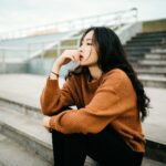 woman wearing brown sweater holding lips