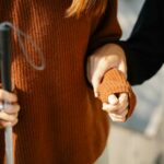 Close-up of two people holding hands, one with a walking cane symbolizing support and visual aid.