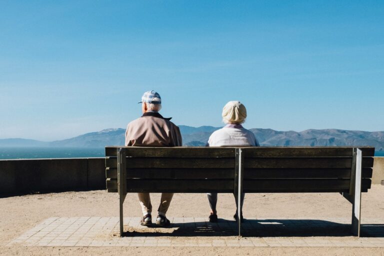 Früh einsetzende Alzheimer-Krankheit man and woman sitting on bench facing sea