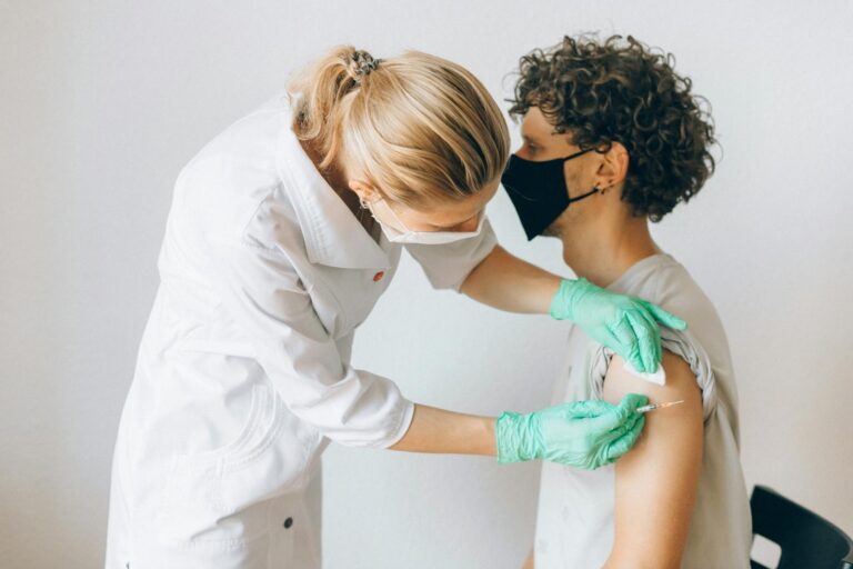 Post-Polio-Syndrom A healthcare worker gives a vaccine shot to a patient wearing a mask, highlighting medical safety and health precautions.