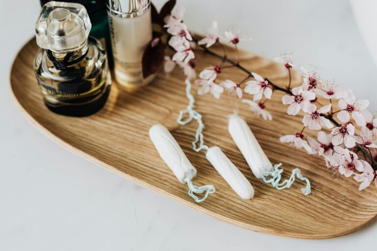 Toxisches Schocksyndrom Flat lay of feminine hygiene products, perfumes, and cherry blossoms on a wooden tray.