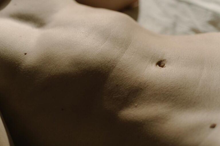 Krebsartige Tumoren der Haut Detailed close-up of human skin featuring belly button, texture, and moles under natural light.