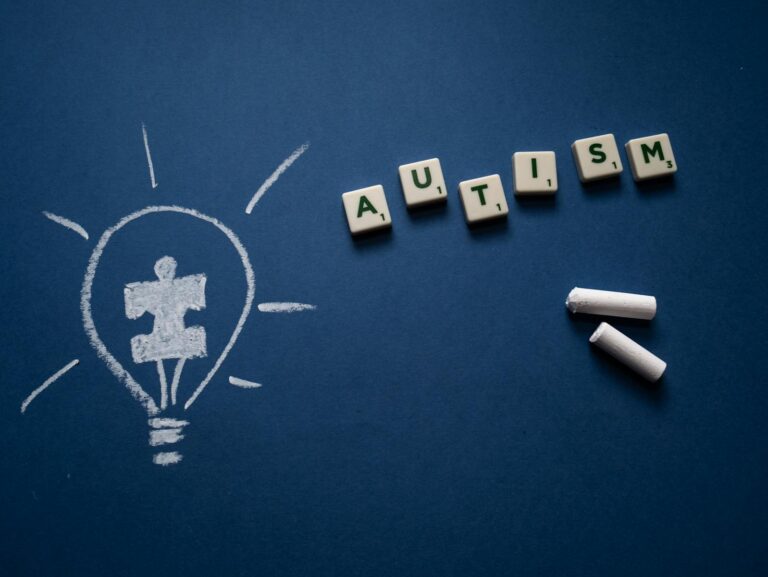 Atypischer Autismus Creative still life highlighting autism awareness with scrabble tiles and chalk drawings.