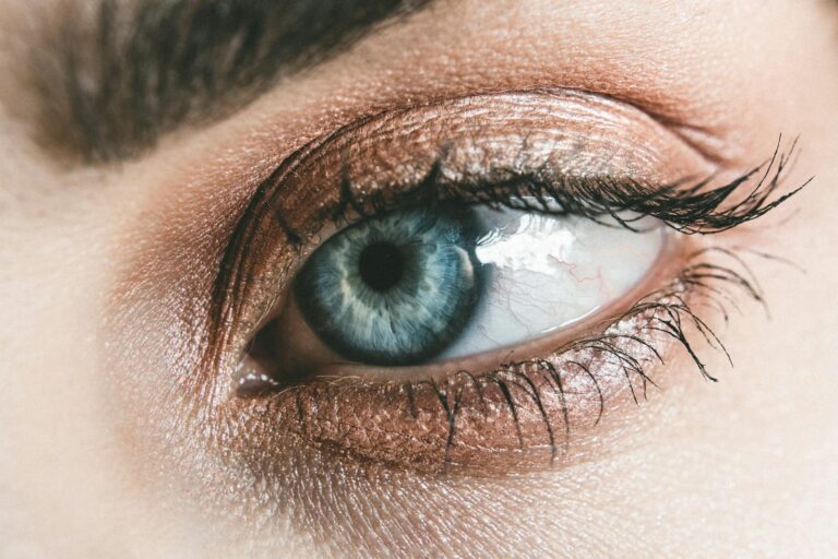Horner-Syndrom Detailed close-up of a woman's blue eye, showcasing makeup and eyelashes.