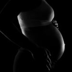 Captivating grayscale close-up of a pregnant woman highlighting a baby bump, conveying anticipation and love.