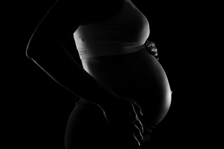 Captivating grayscale close-up of a pregnant woman highlighting a baby bump, conveying anticipation and love.