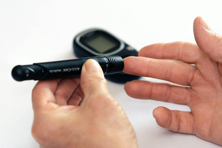 Andere Arten von Diabetes mellitus Close-up image of a person using a glucometer for diabetes management indoors.