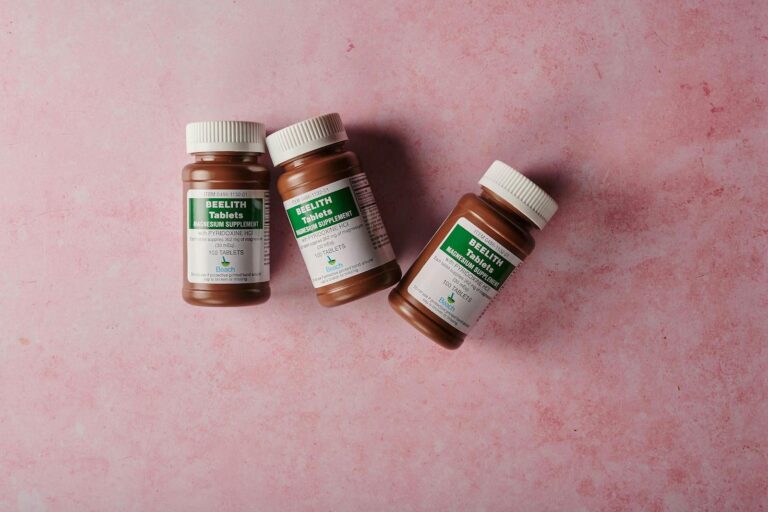 Magnesiummangel Three brown bottles of magnesium tablets on a soft pink background, ideal for health-themed content.