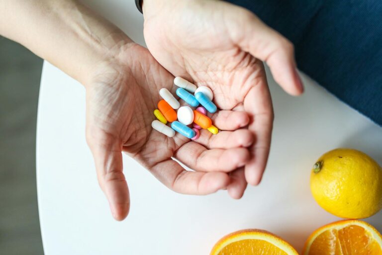 Hypervitaminose A Close-up of hands holding multicolored pills with oranges, symbolizing health and nutrition.